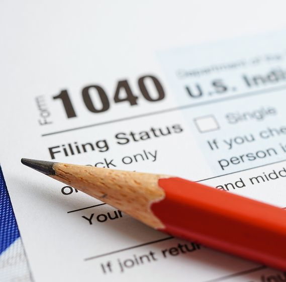 Close-up of IRS Form 1040 with a red pencil resting on the filing status section.