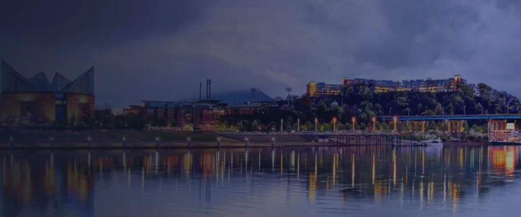 Chattanooga's riverfront at dusk, with the Tennessee Aquarium and city lights reflected in the river.